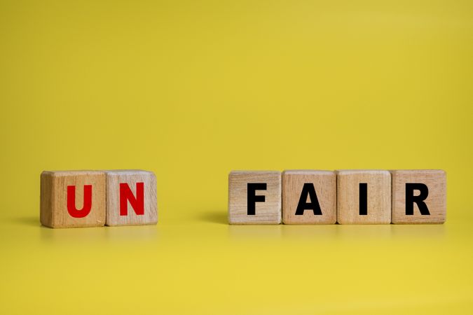 un and fair separated words on wooden blocks isolated on yellow background. concept of fairness