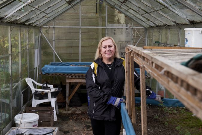 Woman with plant box inside greenhouse