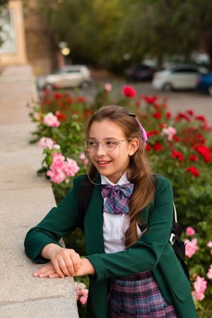 Girl in school uniform surrounded by blooming flowers.