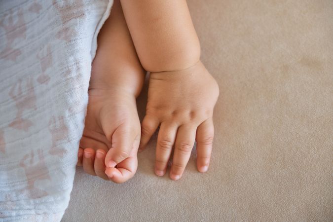 Crop hands of baby sleeping on sofa