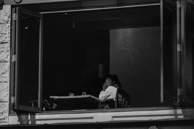 Grayscale photo of woman sitting at table in a restaurant