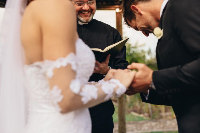 Couple holding hands with groom acknowledging the consent before the priest