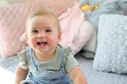 Cheerful little toddler sitting on soft bed looking at camera