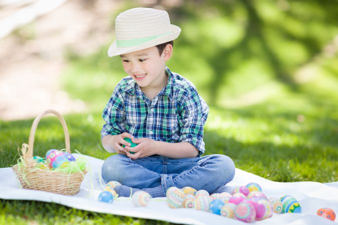 Boy Outside Wearing Rabbit Ears Playing with Easter Eggs