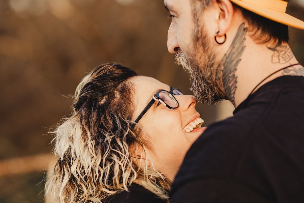 Happy couple hugging and kissing near tree in park