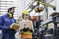 Male and female industrial worker or engineers in hard helmet discussing project