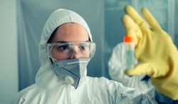 Doctor looking at vial with virus vaccine