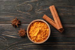Turmeric in bowl with cinnamon sticks and anise, copy space