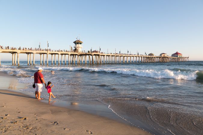 Father and daughter wading by Huntington Beach pier