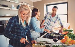 Woman slicing lemons as her friends cook asparagus next to her bxQKv0