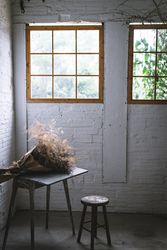 Bunch of plant in paper on table near stool in grey room