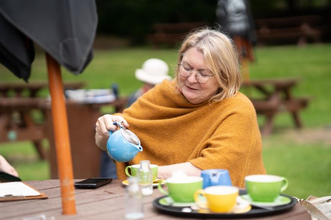 Woman pouring tea at park bench