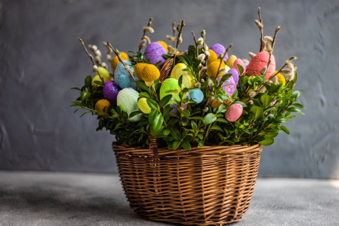 Side view of pastel Easter eggs & leaves in decorative basket