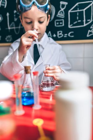 Serious kid playing with chemical beakers