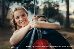 Young girl swinging on a tire swing in a park 0vr9R0