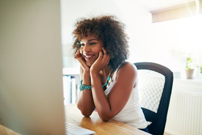 Black female at her home office desk reading computer screen