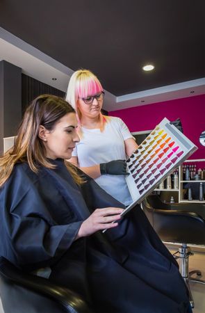 Hairdresser and client choosing hair color from book