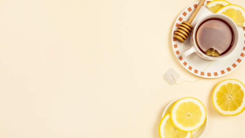 Tea with slice of fresh lemon on beige background