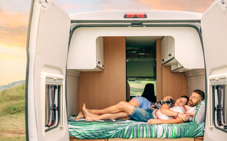 Male and female sleeping on bed in motorhome
