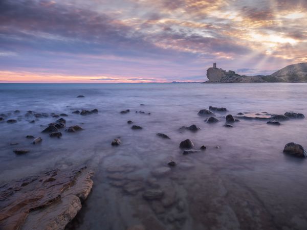 Sundown sky over sea and stony coast