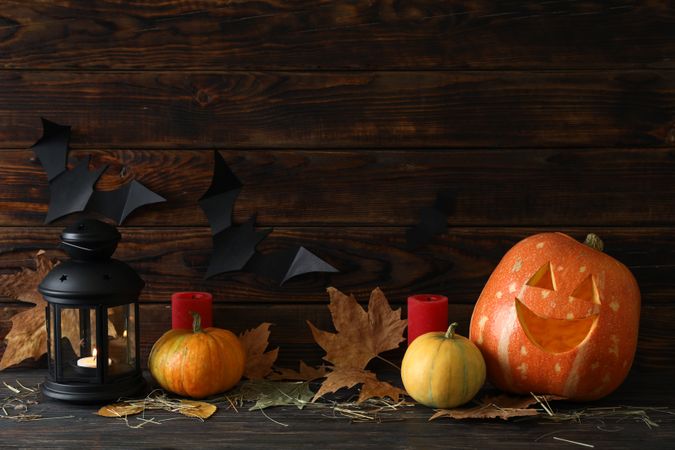 Halloween pumpkins and candles on dark wooden background, copy space