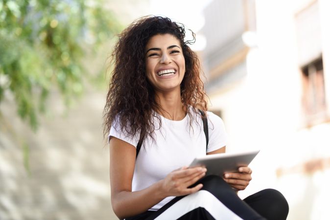 Happy Arab woman with her digital tablet sitting outdoors