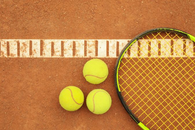 Tennis racquet with tennis balls on clay court