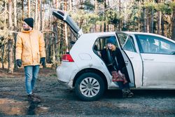 Two people in a forest with car