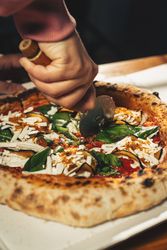 Margherita pizza with basil and tomato served with cold beer on checkered tablecloth