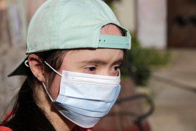 Young girl wearing safety mask over face and looking away