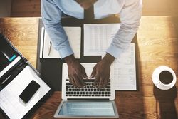 Overhead shot of man in suit and tie working on his laptop