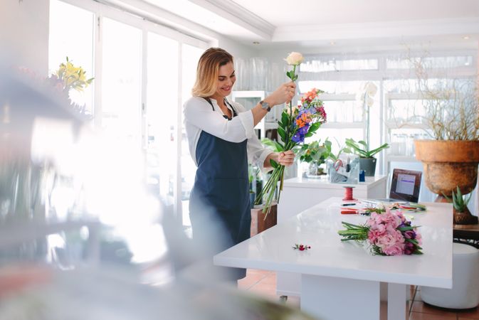 Female florist at work arranging various flowers in bouquet
