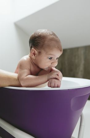 Newborn in the bathtub held by her mother