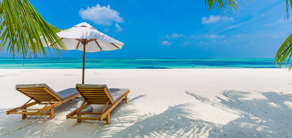 Wide shot of two reclining lounge chairs on an idyllic beach