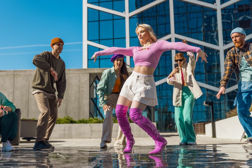 Outdoor Dance Scene With A Young Woman In Pink Leading A Diverse Group Of Friends