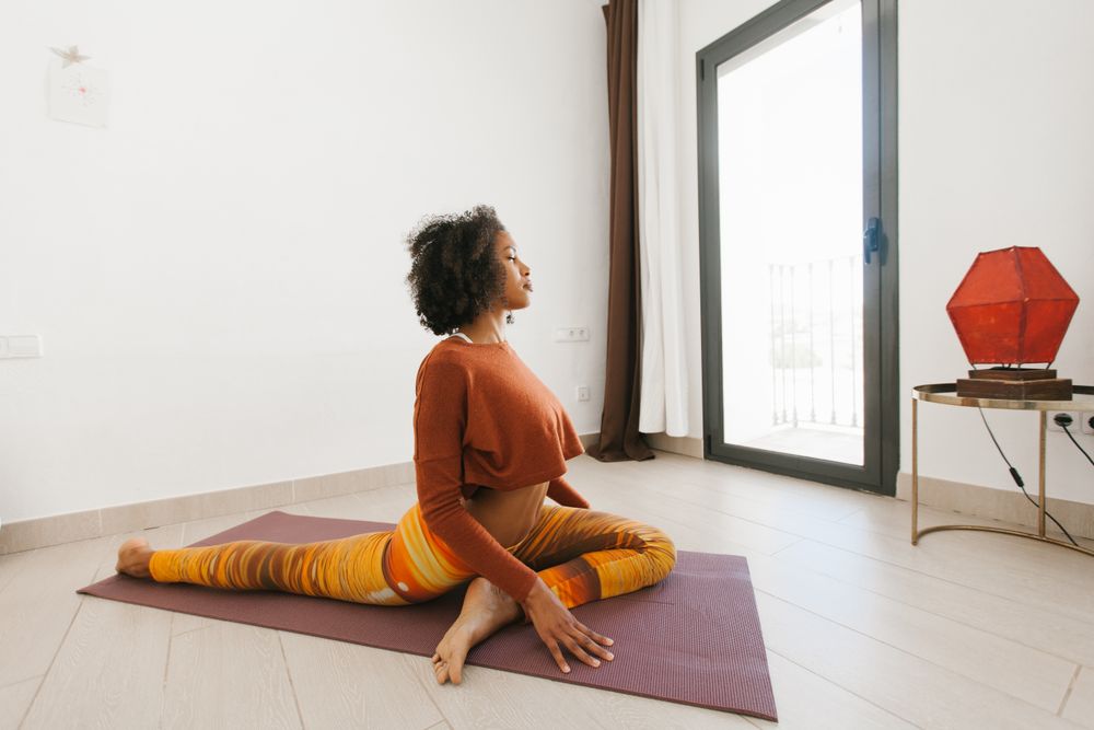 Sportive woman performing yoga pose in room