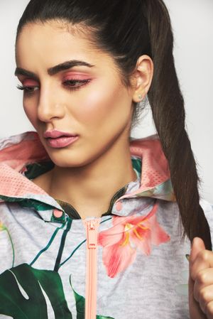 Beautiful woman pictured in colorful printed floral hoodie tugging her ponytail