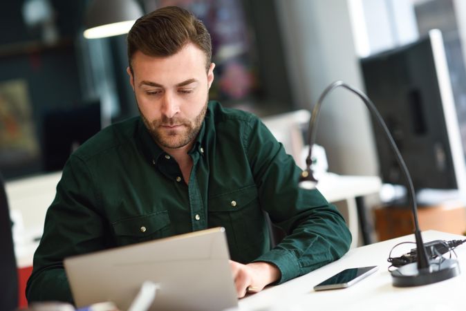 Young man studying with laptop computer in modern office