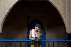 Smiling woman using smartphone on old balcony