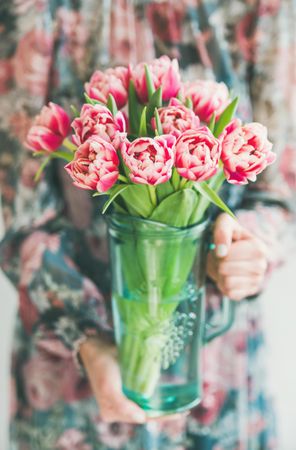 Woman holding clear vase with spring tulip arrangement