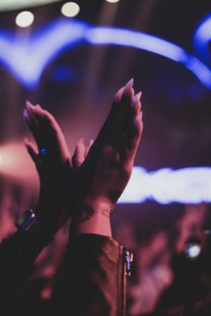 Woman's hands raising at concert during nighttime