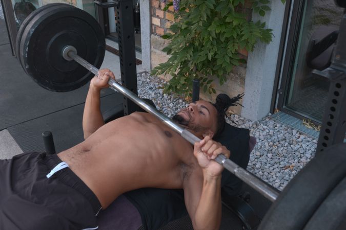 Black guy lifting barbell on street