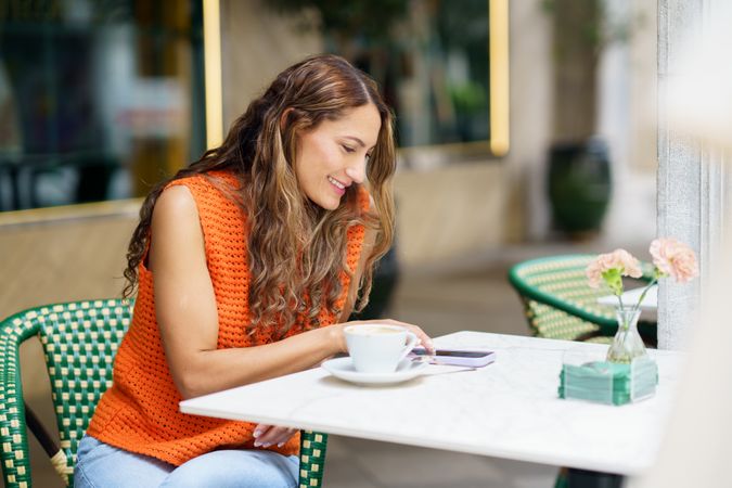 Woman using phone sitting on the terrace of a cafeteria