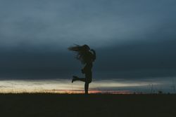 Side view of woman standing in a field and wind in her hair