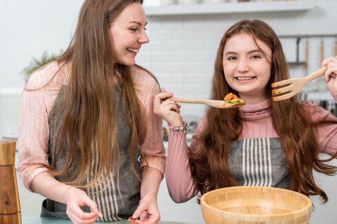 Happy mother and daughter enjoy cooking homemade salad in the kitchen