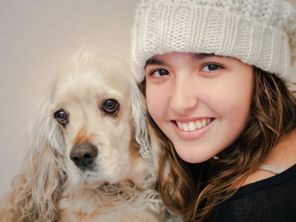 Teen in hat playing with dog