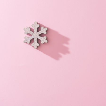 Wooden snowflake Christmas tree decoration with pink background with shadow
