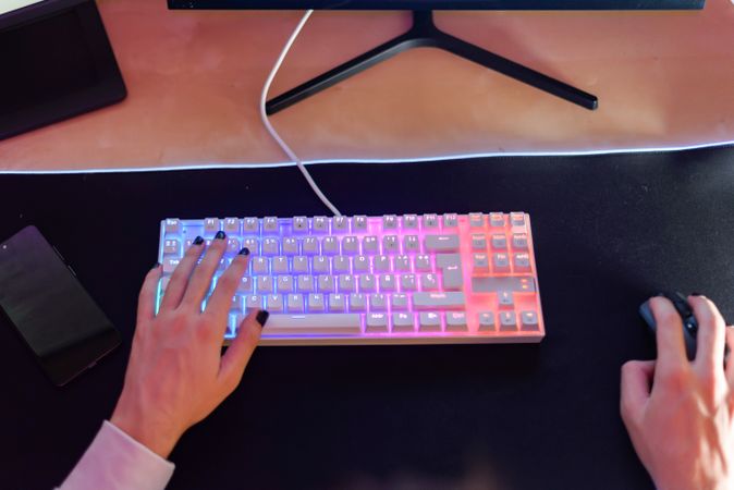 Unrecognizable person sitting with hand on keyboard and using mouse