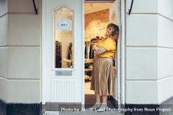 Businesswoman standing at the doorway of her boutique 0LDWe0