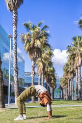 Black female doing bridge under the palms in a promenade